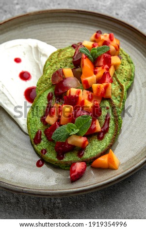 Spinach pancakes with fruits and berries. Delicious, hearty, nutritious breakfast. Balanced nutrition for beauty and health.