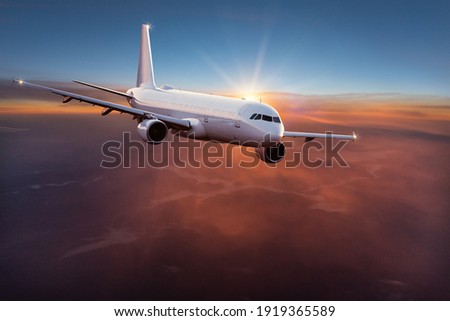 Commercial airplane jetliner flying above dramatic clouds in beautiful light. Travel concept. Royalty-Free Stock Photo #1919365589