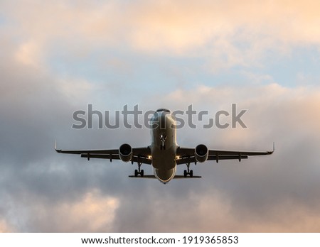 Commercial airplane jetliner flying above dramatic clouds in beautiful light. Travel concept. Royalty-Free Stock Photo #1919365853