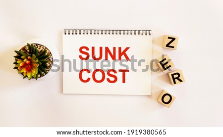 Notepad with the text SUNK COST on a white background. And the word ZERO on the cubes