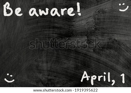 be aware on blackboard note over a dark background. april fools day