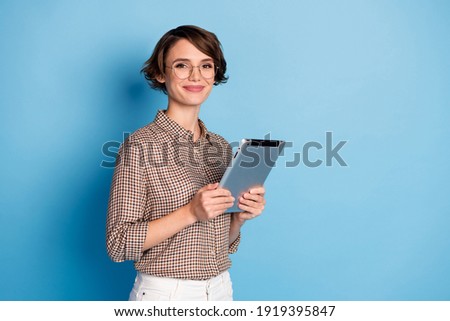 Portrait of half turned nice person smile holding tablet wear checkered outfit isolated on blue color background