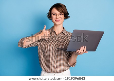 Portrait of positive nice girl hold laptop show thumb up wear checkered isolated on blue color background Royalty-Free Stock Photo #1919396843