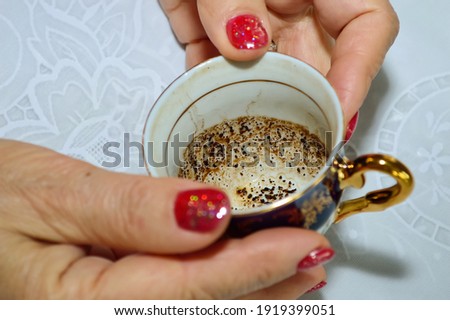 close-up - a fortune teller holds a small coffee cup in her hands, guessing by the coffee grounds