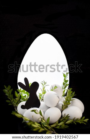 Black silhouette of a rabbit on the background of a glowing silhouette of an egg, Easter bunny, white eggs, chicken eggs, holiday, postcard, unusual photo, creative