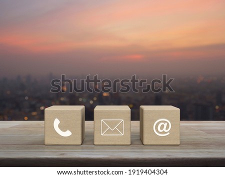 Telephone, mail, email address on wood block cubes on wooden table over blur of cityscape on warm light sundown, Business customer service and support online concept