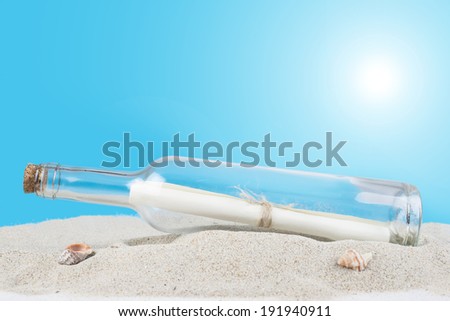 Message on a paper in a bottle half buried in the sand of the beach