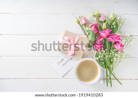 Bouquet of spring, summer flowers, coffee cup and notes good morning, have a nice day on white wooden table. Summer morning beautiful breakfast, greeting card, top view, flat lay. Mother day concept