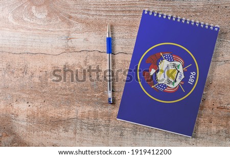 Notepad with Utah flag, pen on wooden background, study concept