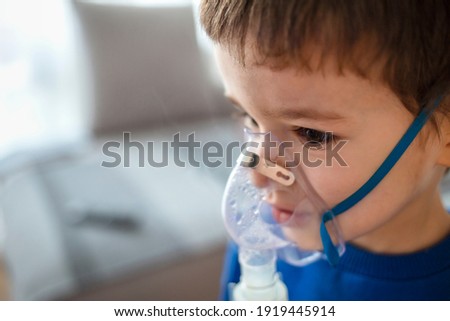 Home treatment. The boy makes inhalation with a nebulizer inhaling medicines into his lungs. Self-treatment of the respiratory tract with inhalation. Little boy using nebulizer during inhaling therapy