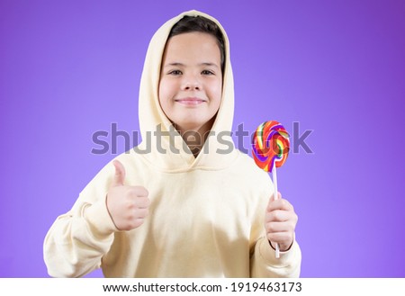 Smiling boy with a lollipop in hand over purple background