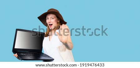 Banner,long format. Surprised girl in summer clothes holds a portable open laptop and shows the boat to the camera. Blue background with space for text and advertising. High quality photo