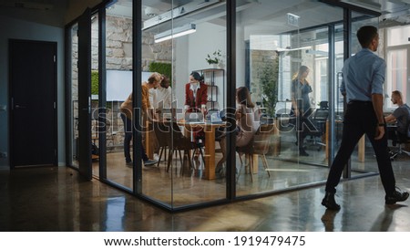 In the Stylish Modern Office Meeting Room: Diverse Group of Business Growth Marketing Professionals Use Computers, Discuss Project Ideas, Brainstorm Startup Company Strategy, Design Creative Product Royalty-Free Stock Photo #1919479475