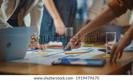Diverse Multi Ethnic Team of Professional Businesspeople Meeting in the Modern Office Conference Room. Creative Team Gathers Around Table to Discuss App Design, Analyze Data. Focus on Desk and Hands Royalty-Free Stock Photo #1919479670