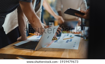 Diverse Multi Ethnic Team of Professional Businesspeople Meeting in the Modern Office Conference Room. Creative Team Gathers Around Table to Discuss App Design, Use Laptop. Focus on Desk and Hands Royalty-Free Stock Photo #1919479673