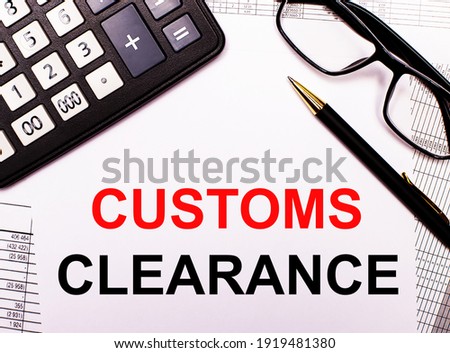 On the reports there is a calculator, glasses, a pen and a notebook with the inscription CUSTOMS CLEARANCE