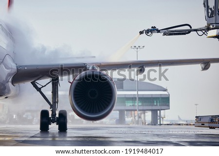 Deicing of aircraft wing before flight. Winter frosty day at airport. 