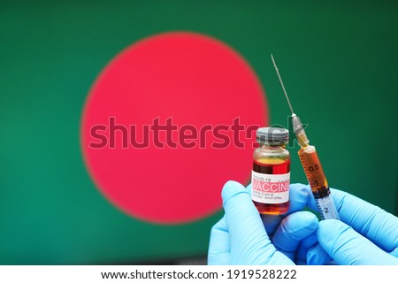 COVID-19 vaccine. Hands in blue medical gloves holding a vaccine bottle and syringe with Bangladesh flag as background