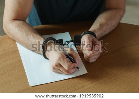 Men hands with handcuffs fill the police record, confession. on top of the police investigative detective. Arrest, bail, criminal, prison. fingerprints, criminal Royalty-Free Stock Photo #1919535902