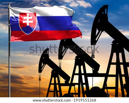Oil rigs against the backdrop of the colorful sky and a flagpole with the flag of Slovakia. The concept of oil production, minerals, development of new deposits.