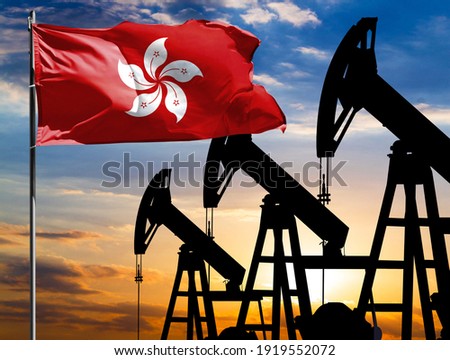 Oil rigs against the backdrop of the colorful sky and a flagpole with the flag of Hong Kong. The concept of oil production, minerals, development of new deposits.