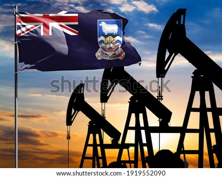 Oil rigs against the backdrop of the colorful sky and a flagpole with the flag of Falkland Islands. The concept of oil production, minerals, development of new deposits.
