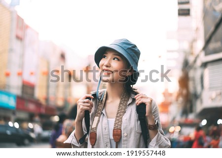 Walking young adult asian woman traveller wear blue hat and backpack. People traveling in city lifestyle at outdoor at chinatown street food market Bangkok, Thailand. Staycation summer trip concept. Royalty-Free Stock Photo #1919557448