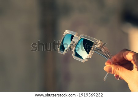 Pixel Model sunglasses hold in hand closeup in a sunny day. Selective focus