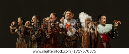 Favorite fast food tastes. Medieval people as a royalty persons in vintage clothing on dark background. Concept of comparison of eras, modernity and renaissance, baroque style. Creative collage. Royalty-Free Stock Photo #1919570375