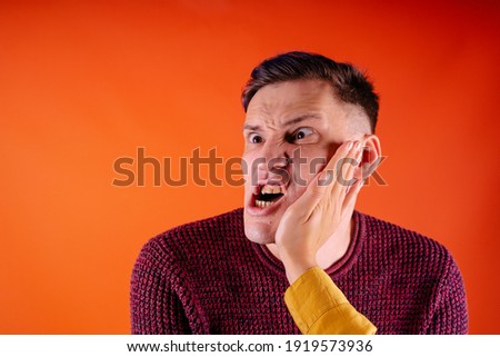 Man getting slapped on orange background. Unhappy scared man getting slapped standing on orange background Royalty-Free Stock Photo #1919573936