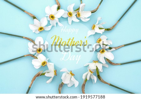 Text Happy Mothers Day. Round frame with spring flowers. Flowers Daffodils in form of wreath on blue background. Leaf pattern. Flat lay, top view