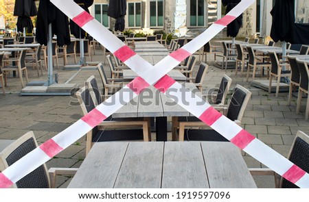 Gastronomy lockdown due to corona epidemic, closed restaurant terrace,chairs, tables and barrier tape, symbolic Royalty-Free Stock Photo #1919597096