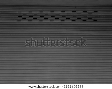 The building door is made of old rolled steel, irregular gray color.