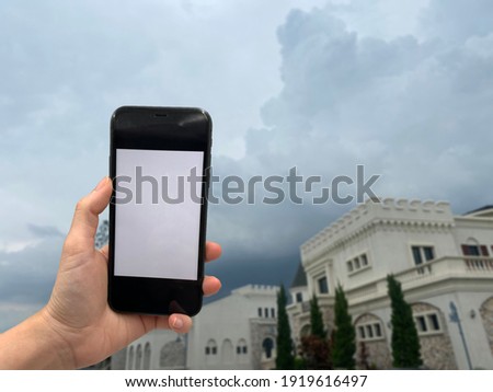 Human hand is holding phone for taking photo with blur castle  background
