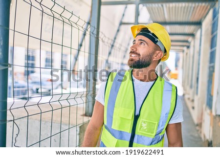 Young hispanic workman smiling happy walking at street of city Royalty-Free Stock Photo #1919622491
