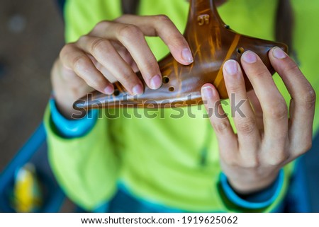 Close-up with the fingers of a young Caucasian woman holding a traditional brown ceramic ocarina in her hands, singing with joy and letting herself be inspired by nature. Royalty-Free Stock Photo #1919625062