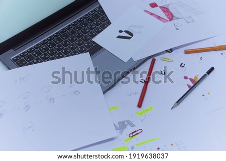 Creative workplace of a Graphic Designer. Development of a logo for the company. Drawings and sketches on paper in a art studio office