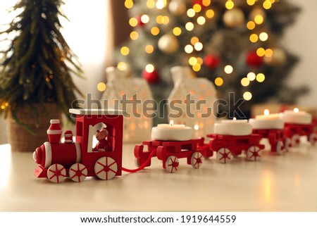 Red toy train as Christmas candle holder on white table in room