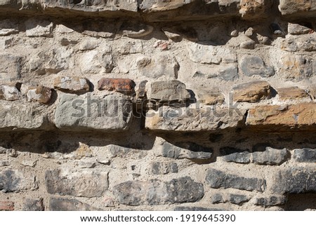 Brick gray wall with embossed rocks, strong light