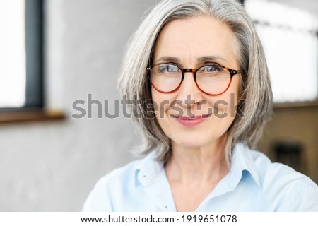 Close-up portrait of charming positive mature elderly business woman wearing stylish eyeglasses and smart casual attire. Senior confident grey-haired lady looks at the camera.  Royalty-Free Stock Photo #1919651078
