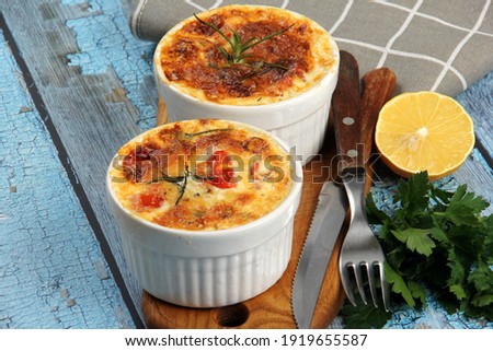 Cod casserole with cheese, sour cream and tomatoes. White fish casserole with cheese and sour cream, Baked fish on pot. Julienne of seafood