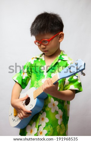 Little Asian boy playing ukulele