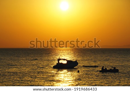 Tropical background with silhouette of boats in yellowish summer sunset