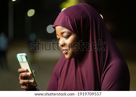 image of traditional  african woman with a smart phone- local muslim lady surfing on social media- outdoor communication concept