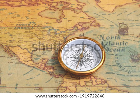 Classic round compass on background of old vintage map of world as symbol of tourism with compass, travel with compass and outdoor activities with compass Royalty-Free Stock Photo #1919722640