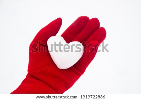 Frozen heart. A heart of snow in a woman's hand in a red glove. Callousness, indifference, coldness