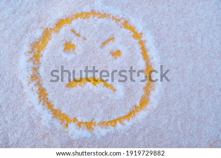 angry unhappy yellow emoticon in winter wet snow. Negative emotion concept.