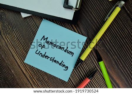 MOU - Memorandum of Understanding write on sticky notes isolated on Wooden Table. Business of Financial concept