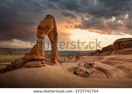 Sunset with stormy skies approaching in Utah, Arches National Park during summertime at Delicate Arch hike with iconic USA landscape.  Royalty-Free Stock Photo #1919742764