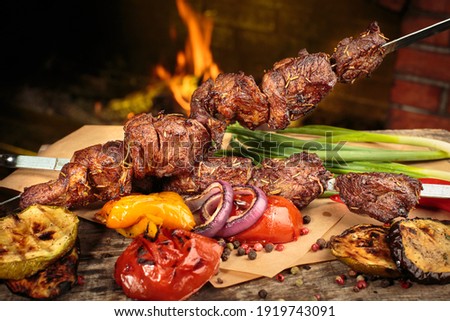 Shashlik or shish kebab prepared on barbecue grill over hot charcoal with grilled vegetables. Grilled pieces of pork meat on metal skewers. Royalty-Free Stock Photo #1919743091